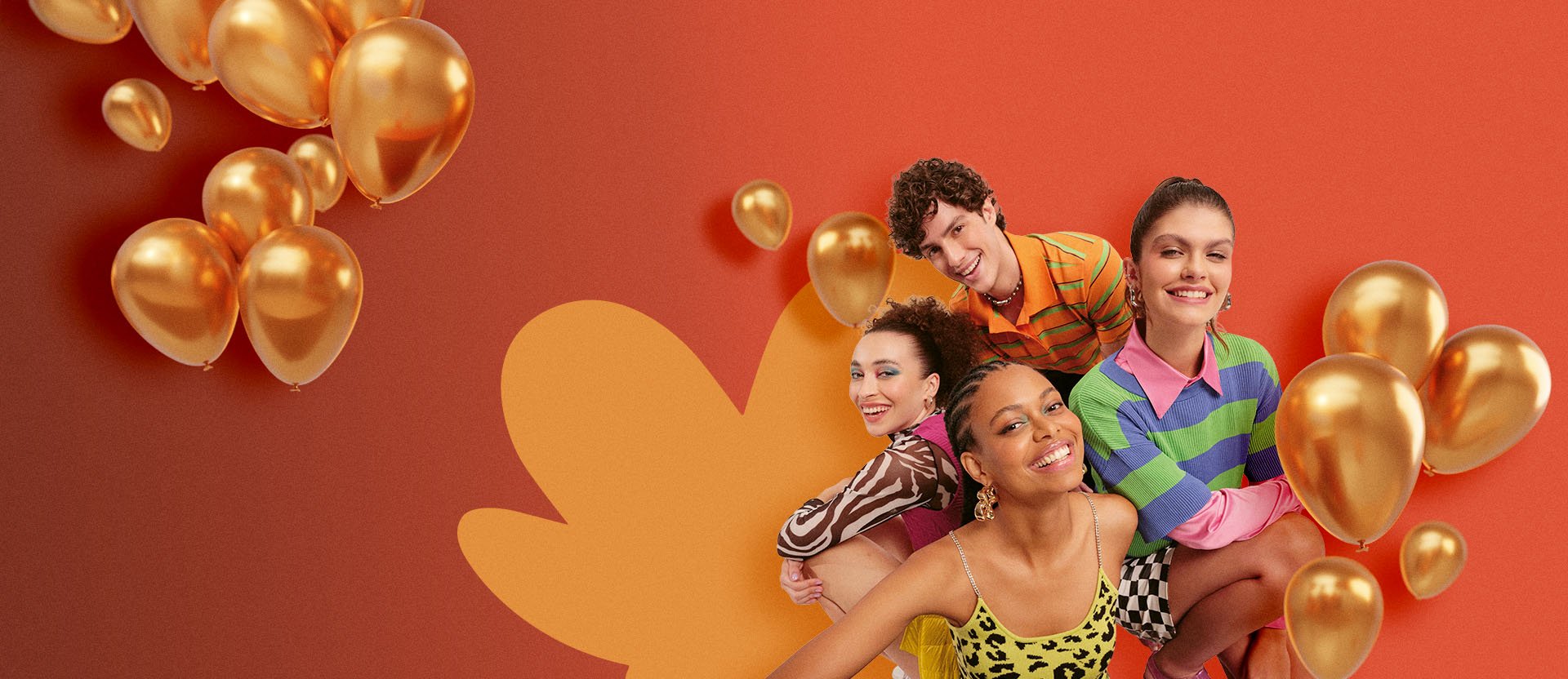 Quatro jovens sorridentes — três mulheres e um homem — posam à esquerda de um fundo laranja vibrante. Eles vestem roupas coloridas com estampas diversas, como animal print e listras. Ao redor do grupo e flutuando à esquerda, há diversos balões dourados metálicos de diferentes tamanhos.