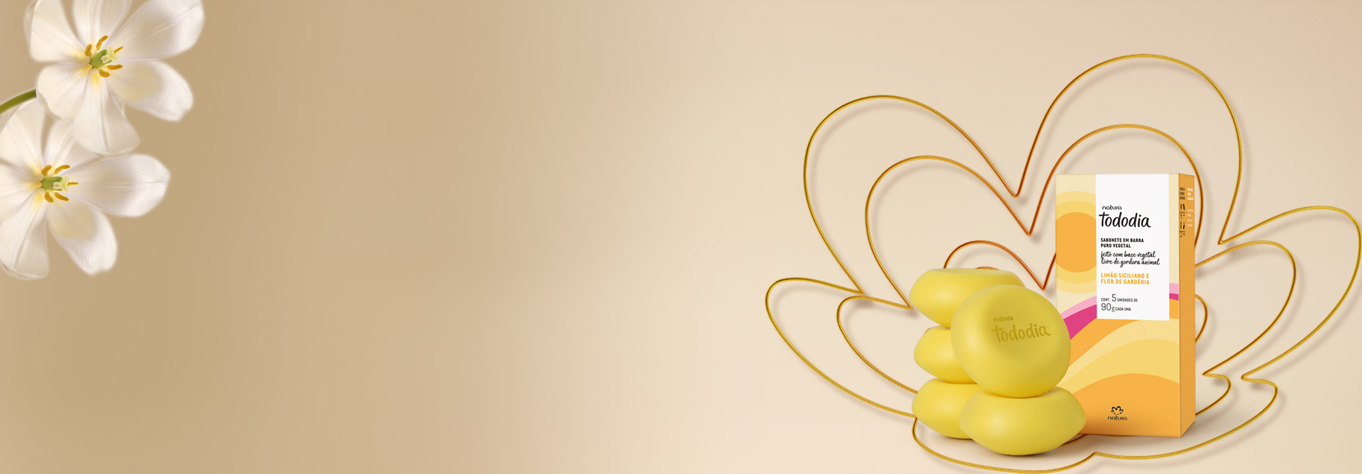 Sabonetes Natura Tododia, com caixa, sobre silhueta da flor da marca Natura em tons de amarelo e laranja, em fundo creme. Abaixo dos produtos, temos as condições da oferta de primeira compra.