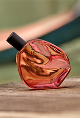 Com tonalidades quentes em vermelho e dourado, Desodorante Colônia Natura Ekos Ryo Chuva repousa sobre madeira. A cena inspira movimento, paixão e a conexão vibrante com a natureza.