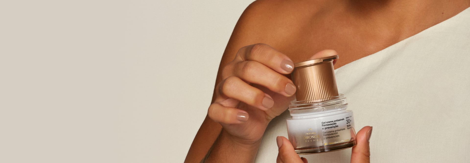 Detalhe de mãos femininas colocando refil dentro de pote de Gel Creme Antissinais Natura Chronos Derma.