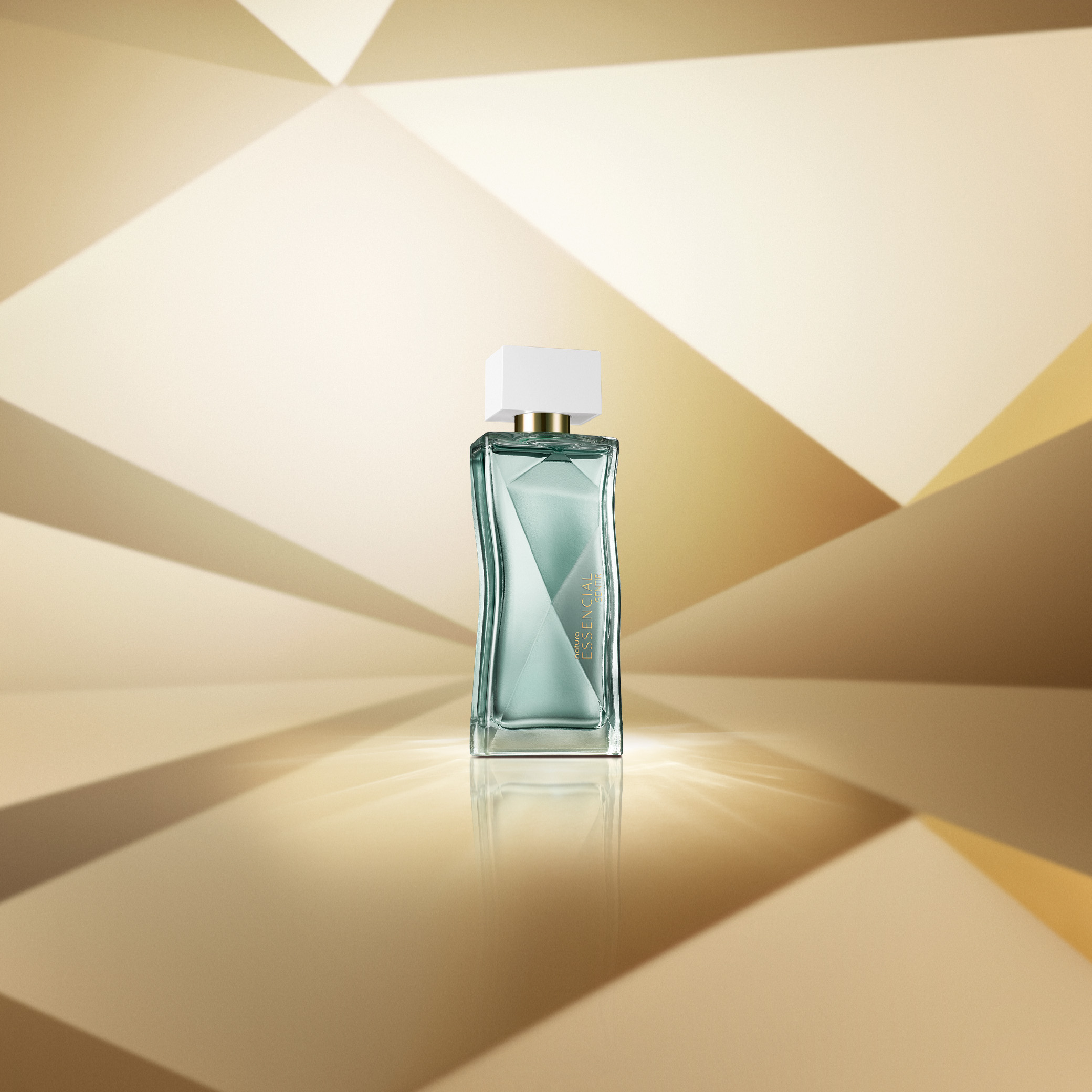 Frasco de perfume Natura Essencial Sentir em vidro transparente com tampa branca. Fundo geométrico em tons de dourado.