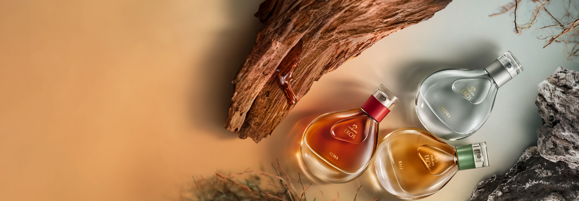 Perfumes Natura Ekos rodeados de ingredientes como madeiras, pedras, raízes e folhas.