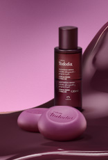 Produtos da linha Natura Tododia Cereja Negra e Praliné sobre forma orgânica na cor vinho e fundo em tons de rosa.