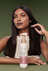 Em fundo verde, produto Natura Lumina à frente de mulher de cabelos longos e lisos.