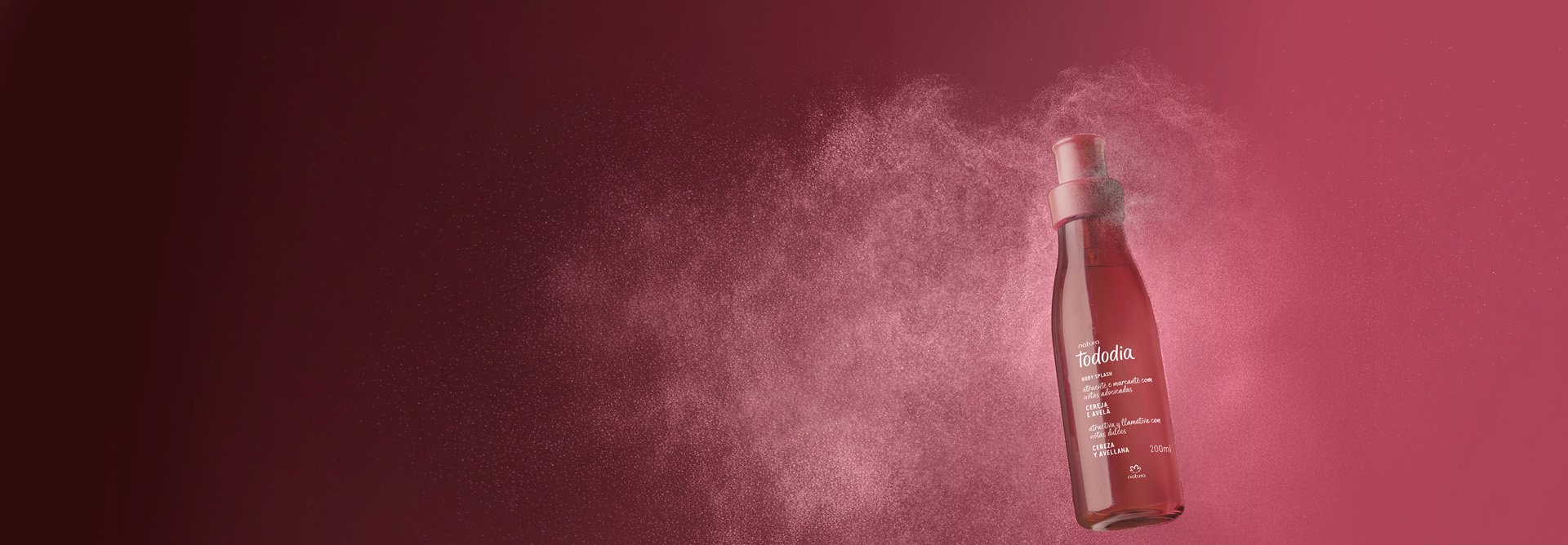 Frasco vermelho do Body Splash Tododia Cereja e Avelã em um fundo vermelho-escuro, com um spray fino de névoa branca ao redor.