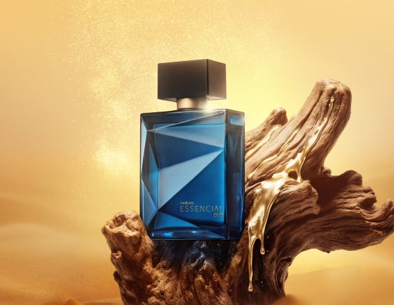 Frasco de Essencial Oud Masculino, em tom de azul-escuro e tampa preta, aparece iluminado em superfície e fundo dourados.
