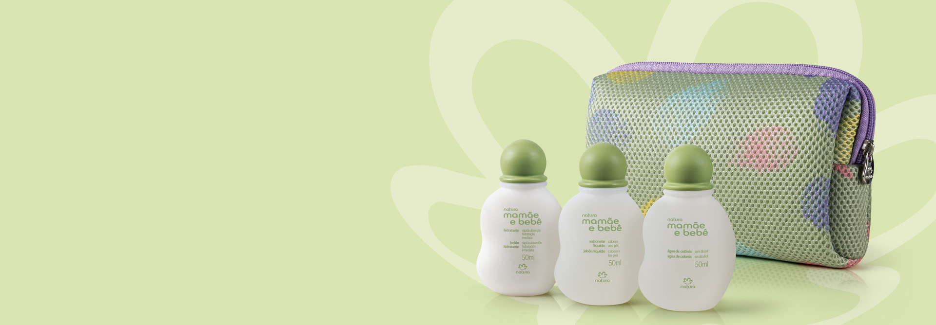 Três miniaturas Natura Mamãe e Bebê dispostas à frente de nécessaire. Os produtos estão em fundo verde claro com a silhueta da marca envolvendo os itens.