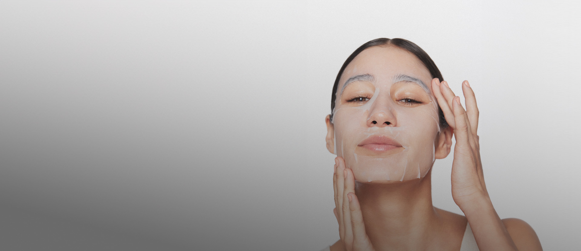 Imagem de mulher com máscara facial Natura Faces, à direita, em fundo branco.