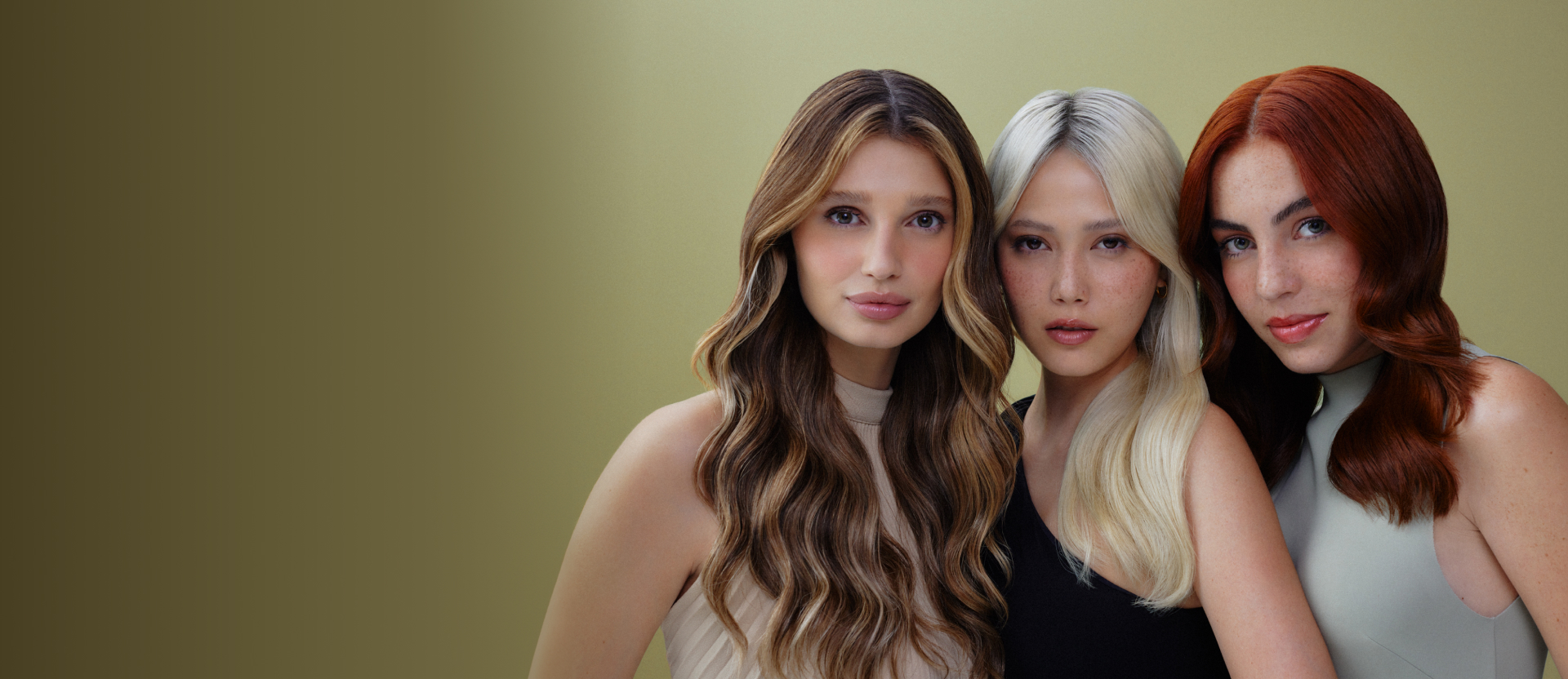 Três mulheres jovens em frente a um fundo dourado degradê. Uma é loira com mechas claras, outra platinada e outra ruiva.