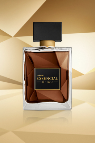 Frasco de Essencial Único Masculino, em vidro translúcido com fragrância em tons de âmbar e tampa preta, aparece iluminado sobre superfície e fundo dourados.