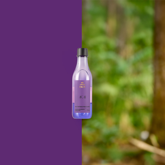 Frasco roxo do Natura Ekos Açaí Óleo Trifásico Hidratante para o Corpo 200 ml ao centro, com metade do fundo roxo e metade mostrando floresta desfocada ao fundo.