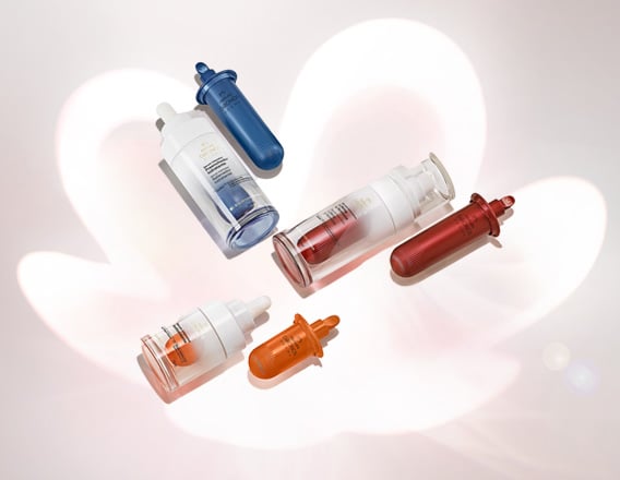 Novos Séruns de Tratamento Intensivo de Natura Chronos Derma com refis em destaque no centro da tela sobre rosácea em fundo branco.