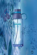 Frasco de Kaiak O2 feminino, em vidro translúcido, apoiado sobre água e respingos em fundo azul.