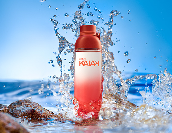 Frasco de Kaiak feminino em laranja. Fundo com água e respingos formando ondas.