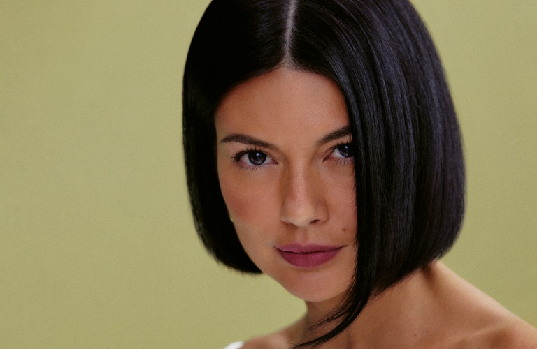 Mulher com cabelo liso preto e curto, usando um vestido branco