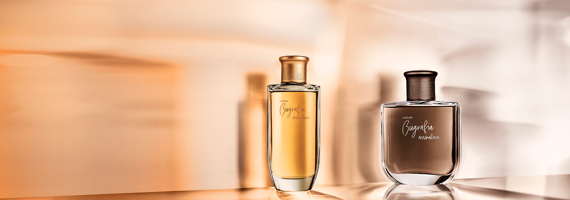 Imagem com reflexos em dourado e marrom e as fragrâncias masculina e feminina da linha Biografia assinatura