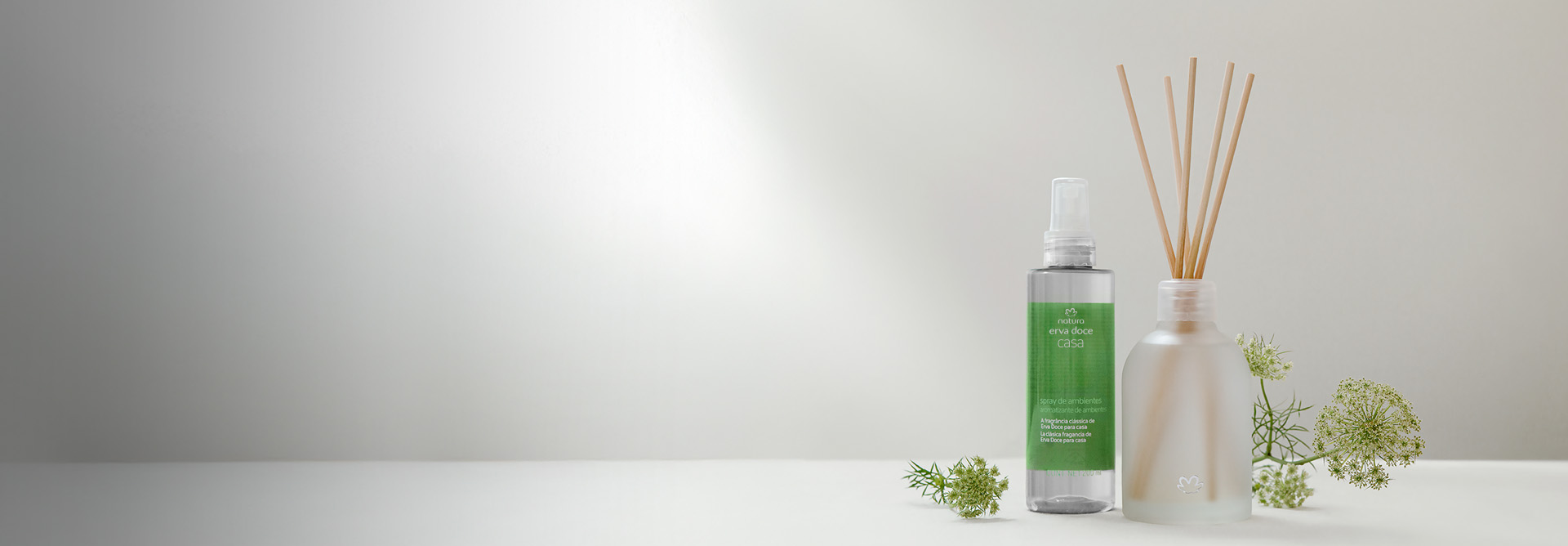 Spray para Ambientes e Difusor de Ambiente em bancada branca com flores de erva doce em fundo branco.