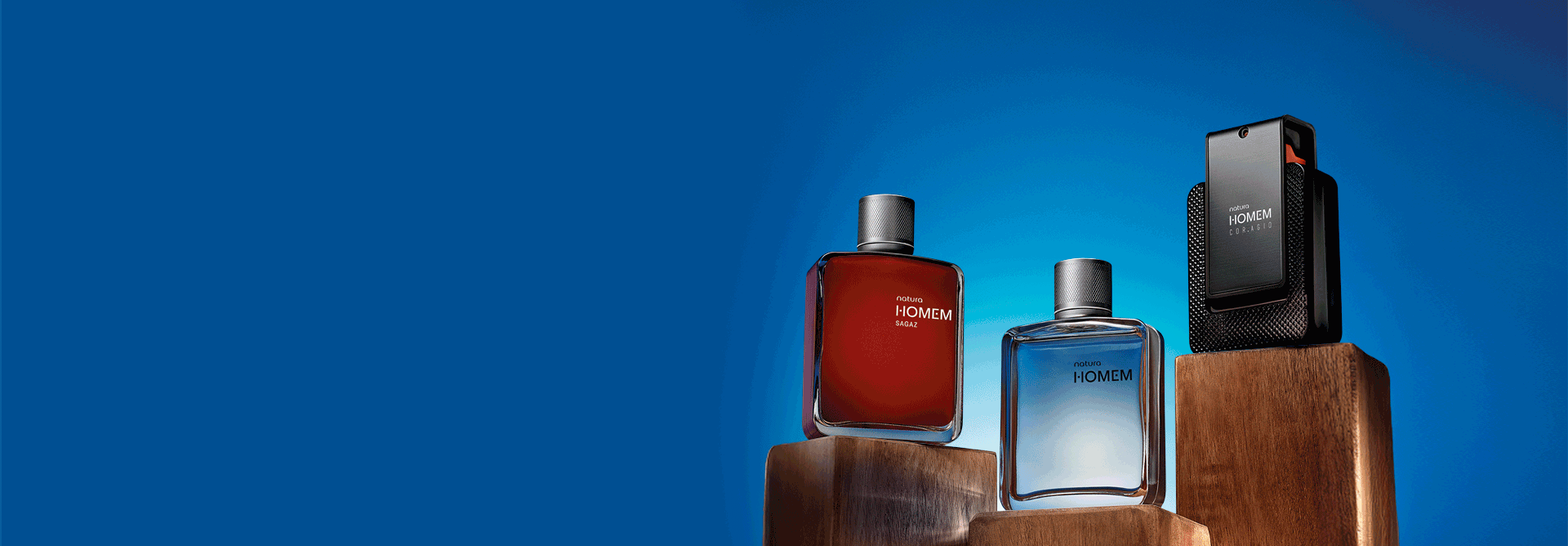 Frascos de fragrâncias Natura Homem: Sagaz em vermelho, Homem azul-claro, Cor.agio preto, Essence azul-escuro, Elo azul-claro e Nós laranja, alternando sobre três madeiras retangulares, em fundo azul.