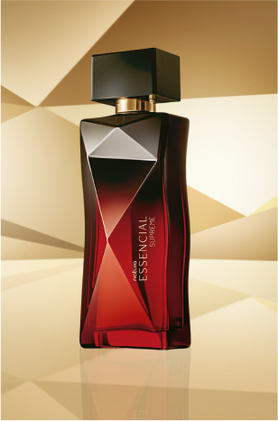 Frasco de Essencial Supreme Feminino, em tons de vermelho e preto com tampa preta, aparece no centro da tela sobre fundo multifacetado dourado, fazendo alusão ao design do frasco de Essencial.