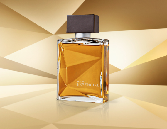 Frasco de Essencial Masculino, em vidro translúcido com fragrância em tons de âmbar e tampa preta, aparece em destaque sobre superfície e fundo em tons de dourado.