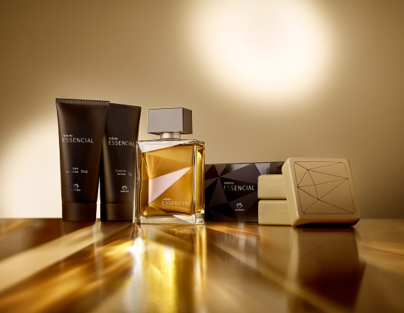 Presente Essencial Masculino com Balm Pós-barba, Creme de Barbear, Deo Parfum e três Sabonetes em Barra aparece iluminado sobre superfície dourada em fundo dourado.