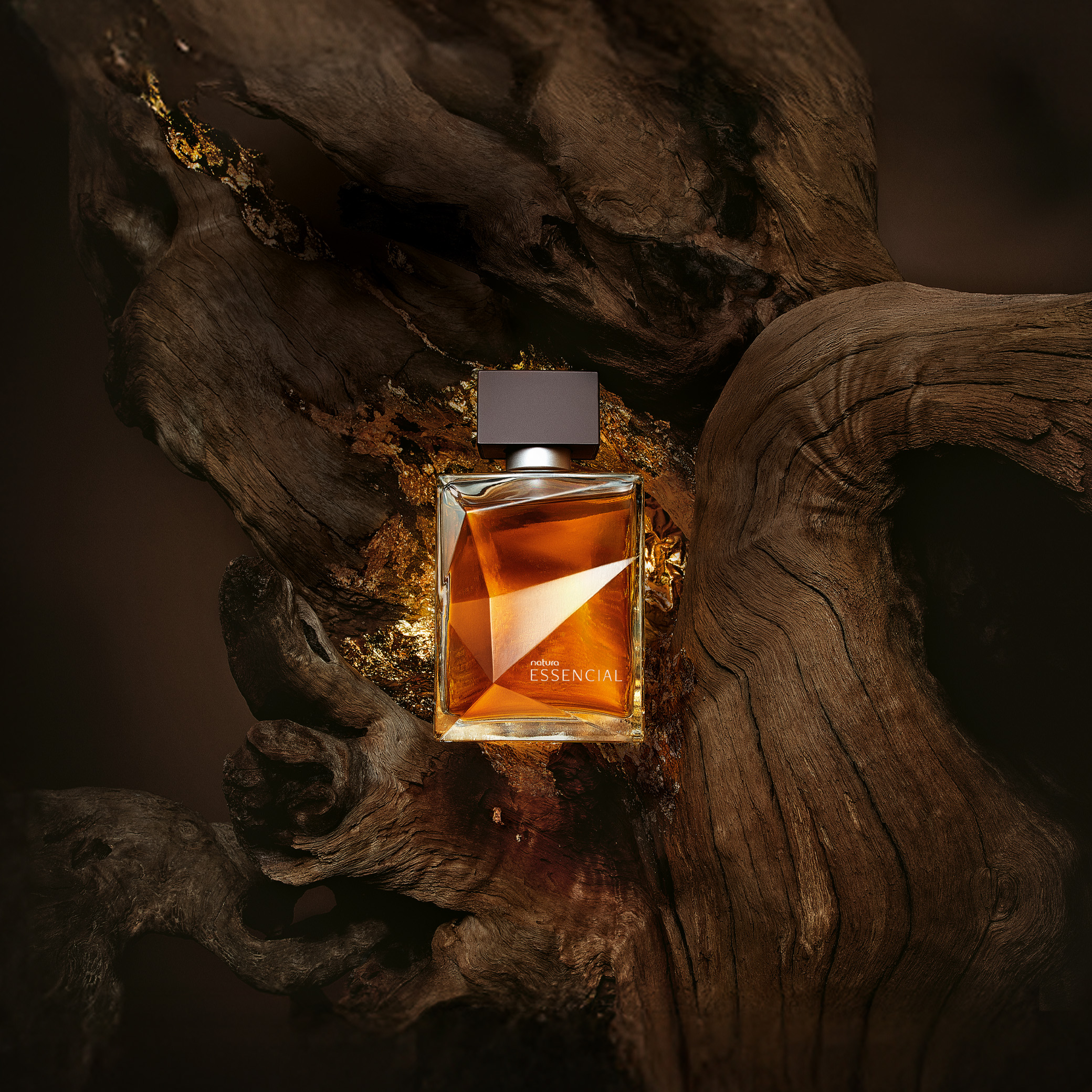 Frasco do Deo Parfum Essencial masculino em destaque sobre fundo com madeiras e detalhes dourados. 