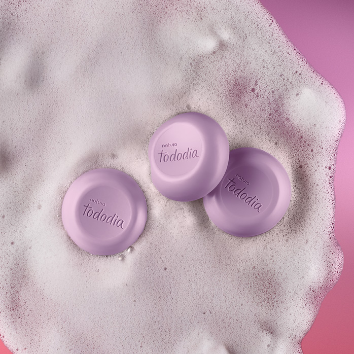 Sabonetes Natura Tododia sobre espuma branca em fundo rosa.