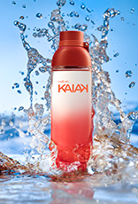 Frasco de Kaiak feminino em laranja. Fundo com água e respingos formando ondas.