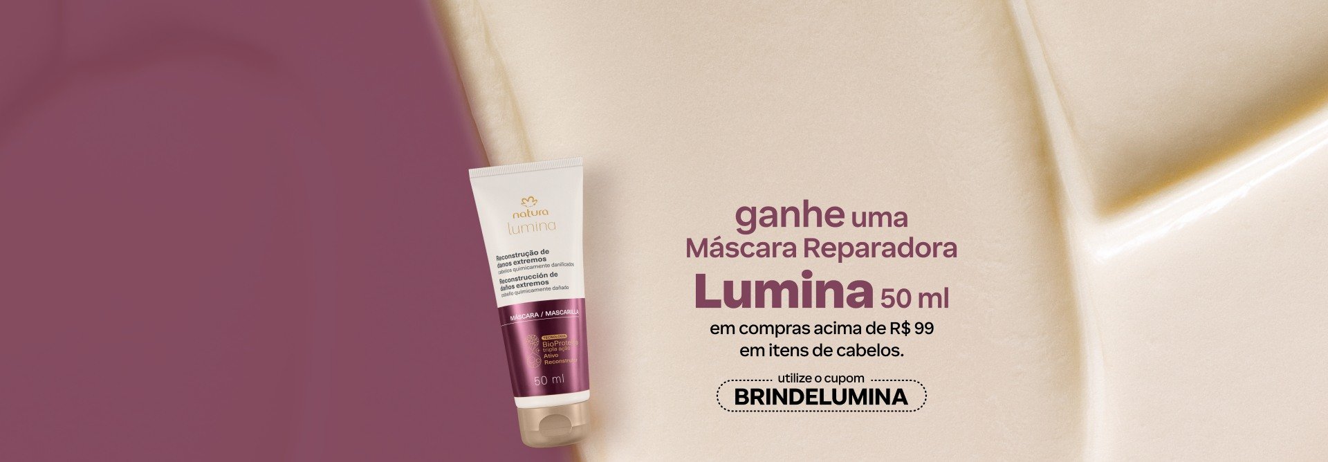 Bisnaga branca com rótulo vinho de Máscara Reparadora Lumina com o texto: ganhe uma Máscara Reparadora Lumina 50 ml em compras acima de R$ 99 em itens de cabelos. Utilize o cupom BRINDELUMINA. Fundo vinho com textura cremosa.
