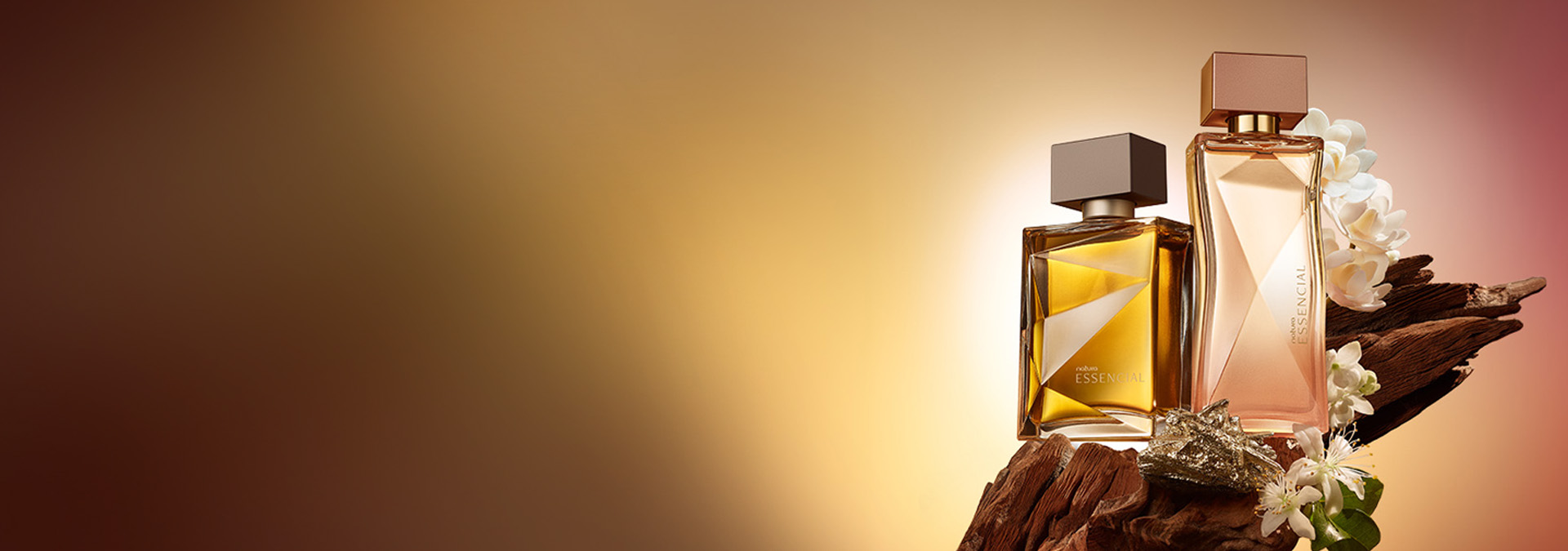 Natura Essencial masculino e feminino sobre tronco de madeira com flor de laranjeira, em um fundo degradê em tons de dourado.