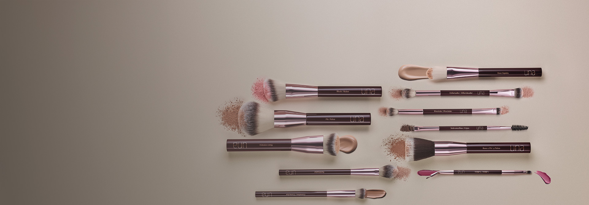 Os onze pincéis profissionais de Natura Una aparecem na posição horizontal com amostras de blush, pó, sombras e batons em fundo bege-claro.