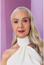 Foto de mulher de cabelos grisalhos e soltos, em fundo lilás.