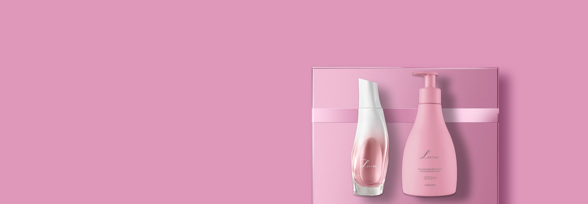 Frasco de fragrância e embalagem de Hidratante Corporal Perfumado Natura Luna sobre caixa com fita rosa, em fundo rosa.
