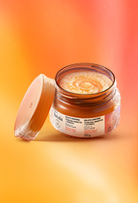 Pote laranja aberto de Gelato Corporal Tododia Manga Rosa e Água de Coco sobre fundo em tons alaranjados. O item tem conteúdo laranja com textura congelada, assim como sua base e tampa.