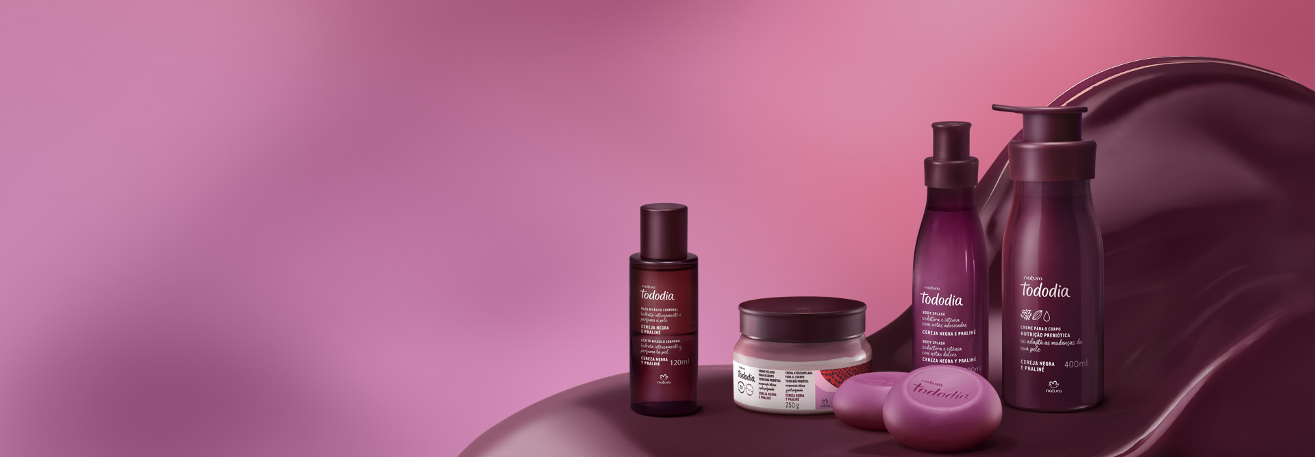 Produtos da linha Natura Tododia Cereja Negra e Praliné sobre forma orgânica na cor vinho e fundo em tons de rosa.