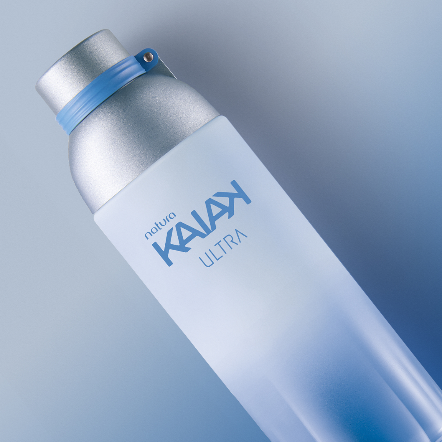 Desodorante Colônia Kaiak Ultra Masculino deitado sobre fundo degradê azul e branco. Frasco de vidro degradê azul com tampa prata.