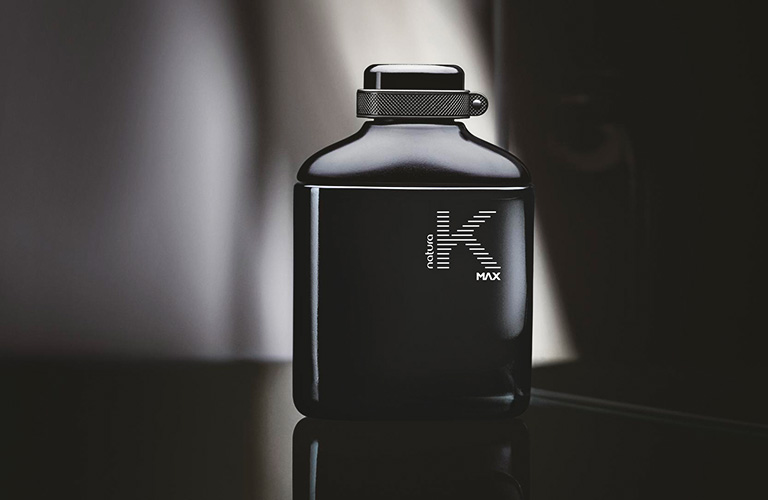 Perfume para trabalhar K Max Masculino sobre um fundo preto com feixe de luz passando atrás do produto