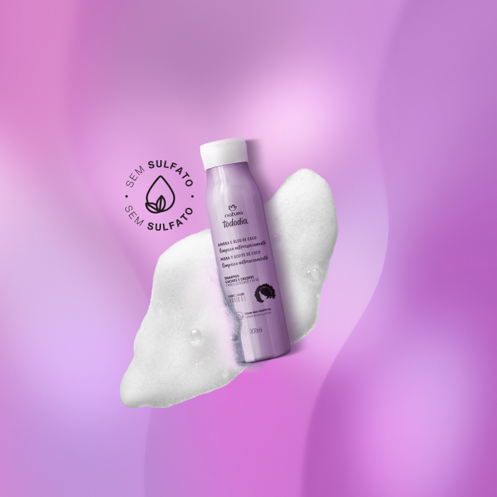 Shampoo Natura Tododia Cachos e Crespos sobre espuma branca,  em fundo roxo, com selo Sem Sulfato ao lado do produto.