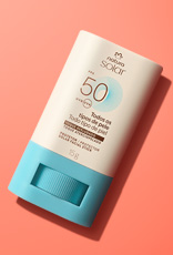 Embalagem stick com base azul e tampa creme de Natura Solar Facial FPS 50 para todos os tipos de pele, em fundo laranja