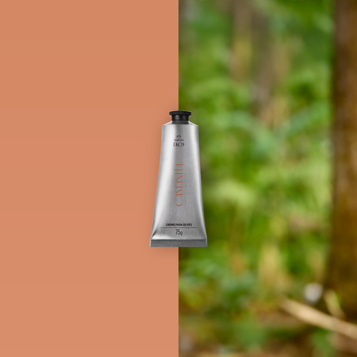 Bisnaga prateada de Creme para os pés  Ekos Castanha 75 g está apoiada sobre um tronco de árvore, cercada por folhas verdes e vegetação densa de floresta ao fundo.