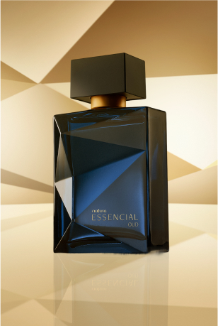 Frasco de Essencial Oud Masculino, em tom de azul-escuro e tampa preta, aparece iluminado em superfície e fundo dourados.