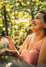 Mulher segurando produto Natura Ekos Andiroba em ambiente amazônico.