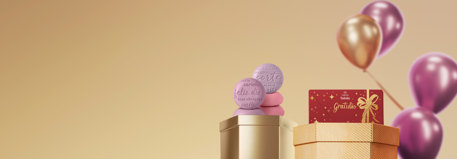Presente Natura Tododia Sabonetes, com sabonetes lilazes e rosas com frases de afeto e caixa vermelha com texto "gratidão", sobre caixas hexagonais. Atrás, balões rosas e dourados em fundo amarelo.