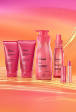 Itens Tododia Acerola e Hibisco, em rosa: bisnagas dos tons de Iluminador, frasco de Creme Sorbet, frasco de Body Splash e embalagem aberta de Balm Labial sobre grafismo e fundo em laranja.