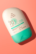 Embalagem creme com tampa verde Natura Solar Facial FPS 70 para pele mista a oleosa, sobre fundo laranja.