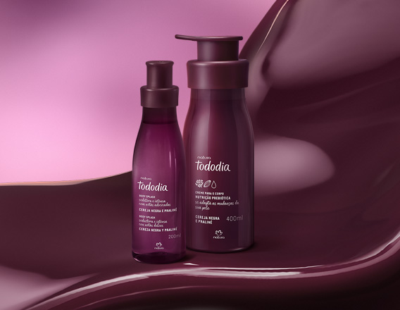 Produtos da linha Natura Tododia Cereja Negra e Praliné sobre forma orgânica na cor vinho e fundo em tons de rosa.