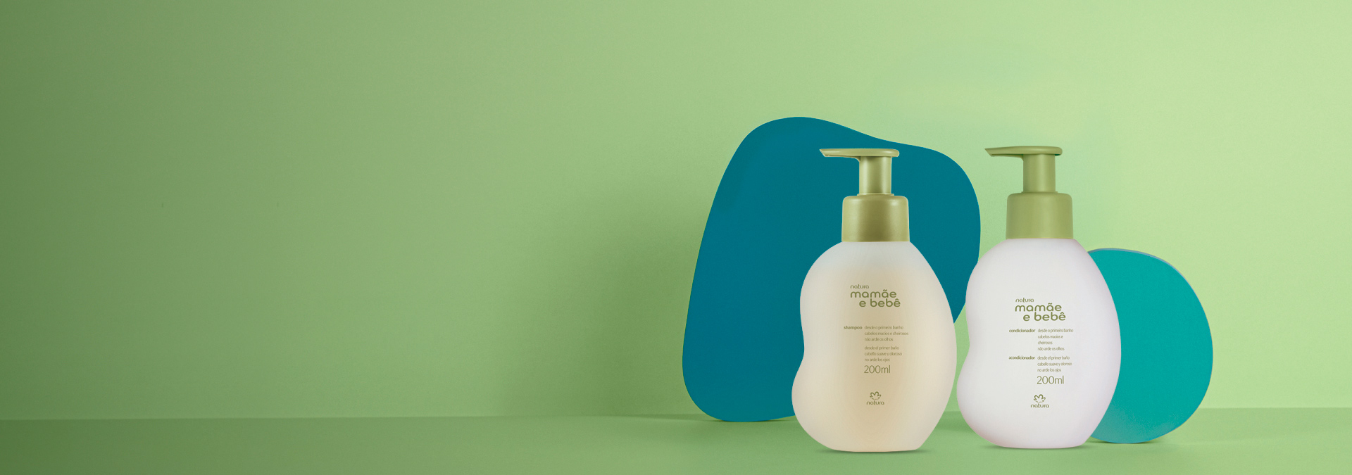 Fundo em tons de verde e ao lado direito um shampoo e um condicionador Natura Mamãe e Bebê