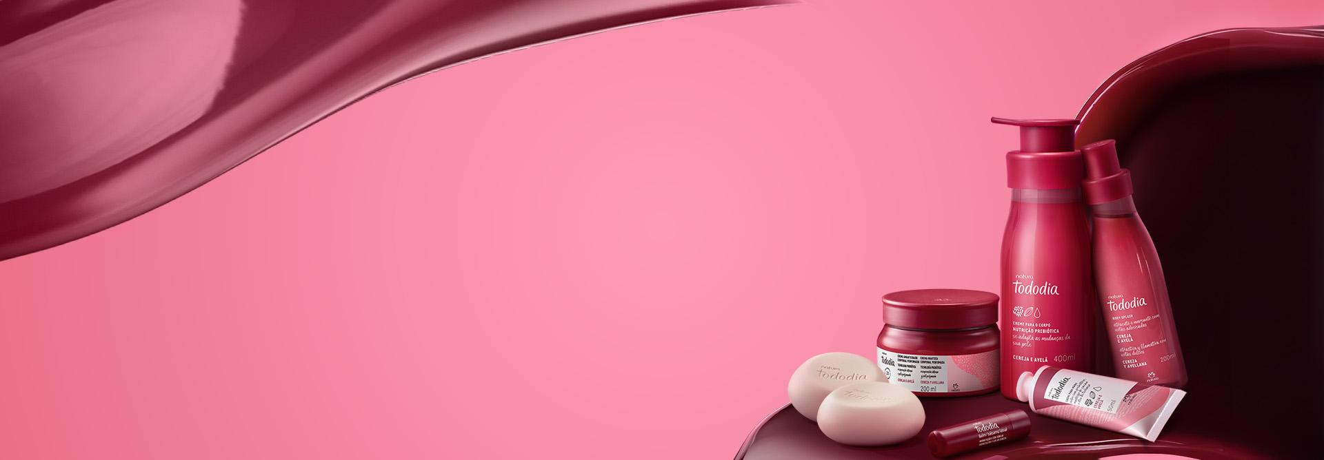 Produtos Natura Tododia Cereja e Avelã sobre formas orgânicas em vermelho, à direita, em fundo rosa.