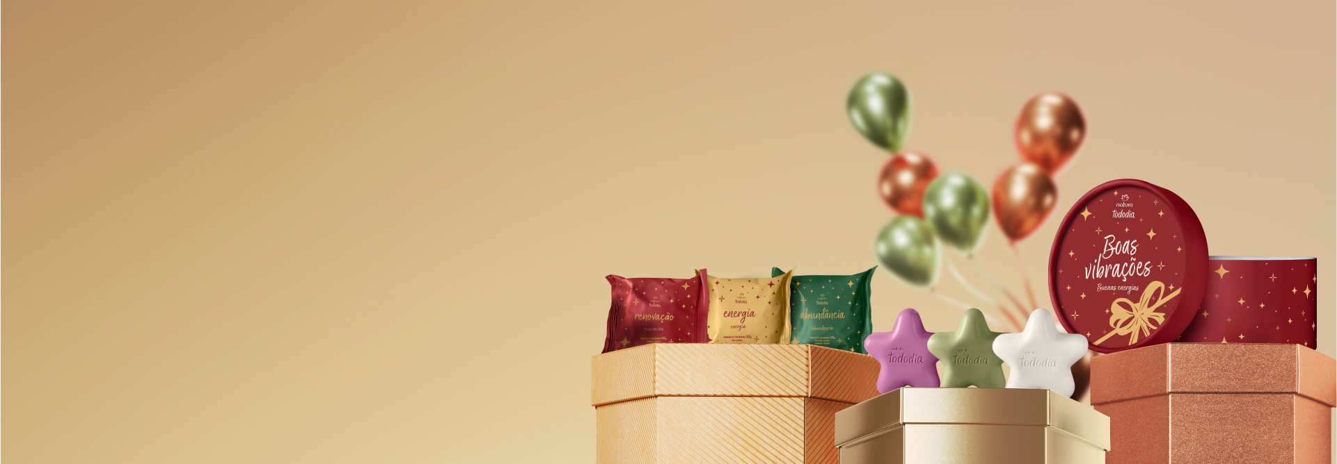 Presente Natura Tododia Sabonetes Miniaturas Estrelas, caixa de sabonetes com 6 unidades nas cores rosa, verde e branco, sobre caixas de presente metalizadas. Fundo dourado com balões coloridos.