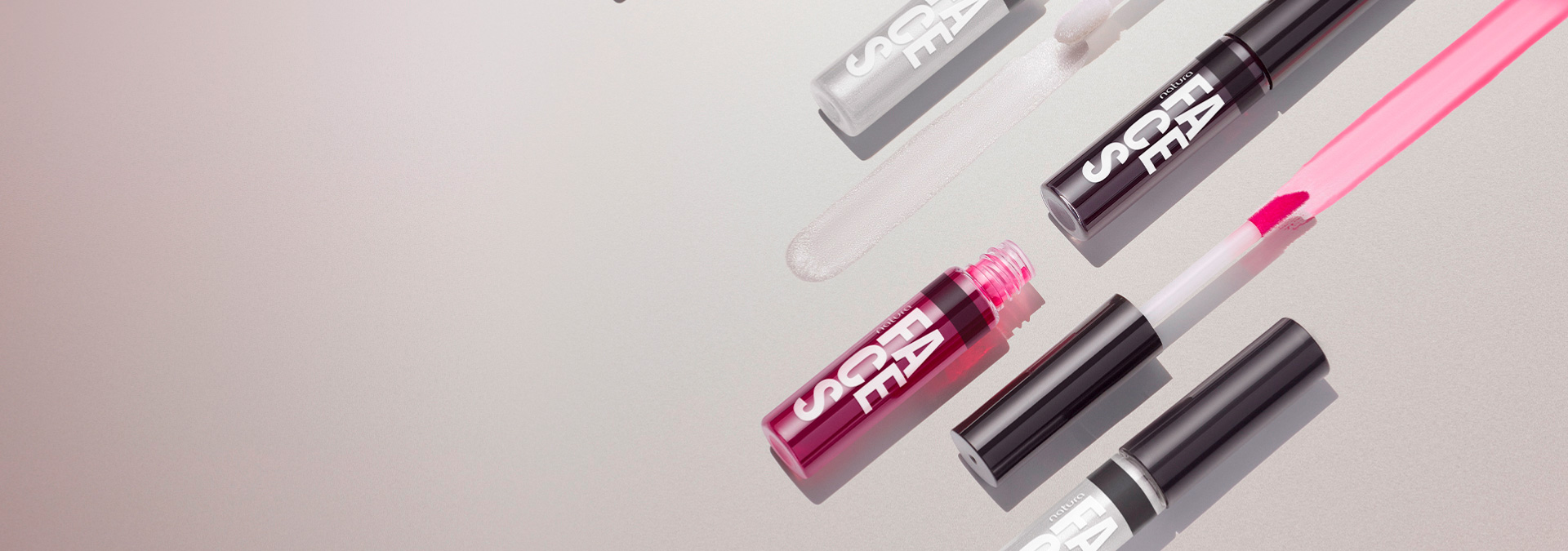 Fundo em tons claros e embalagens de Lip Tint ao lado direito deixando aparente a cor e textura do produto.